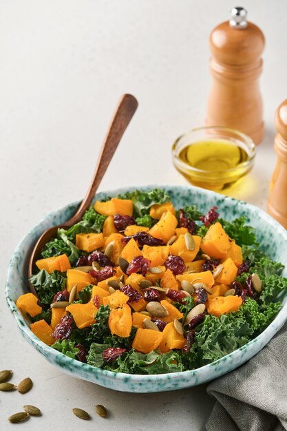 Herbstsalat mit Grünkohl, geröstetem Kürbis, Samen und getrockneten Preiselbeeren in einer Schüssel.