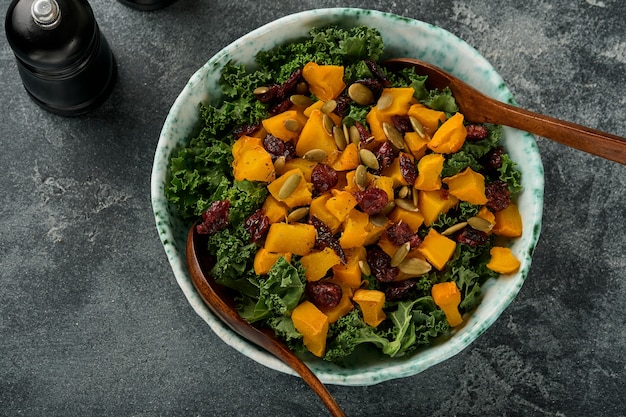 Herbstsalat mit Grünkohl, geröstetem Kürbis, Samen und getrockneten Preiselbeeren in Schüssel.