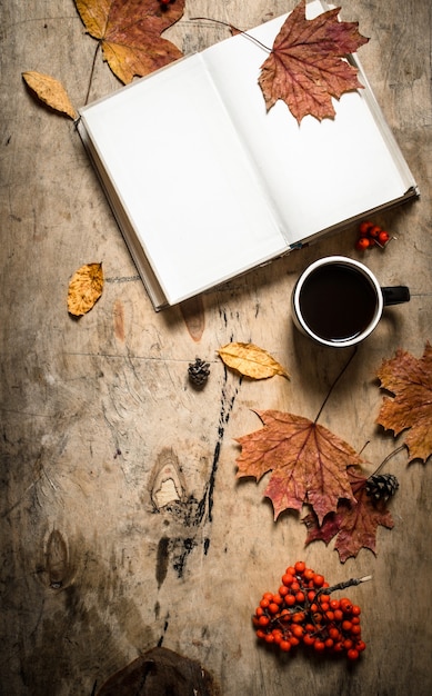 Herbststil. Öffnen Sie das Buch mit einer heißen Tasse Kaffee. Auf hölzernem Hintergrund.