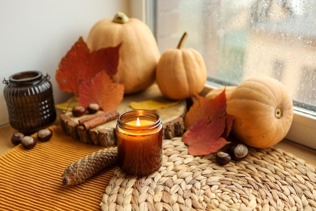 Herbststillleben auf der Fensterbank eine brennende Kerze, Kürbisse und Kerzen