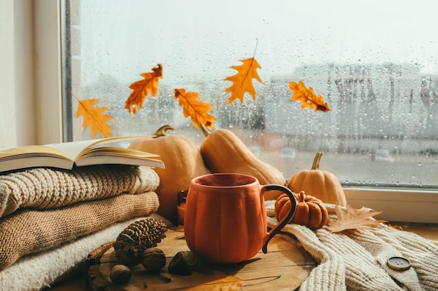 Herbststillleben auf der Fensterbank eine Tasse Teekerzen Kürbisse Blätter Thanksgiving House Interior