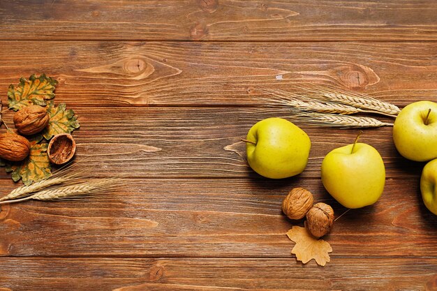 Herbststillleben mit Apfel-Pfirsich-Gerstenohren, Ahorn und Eichenblättern, Walnüssen auf Holzhintergrund