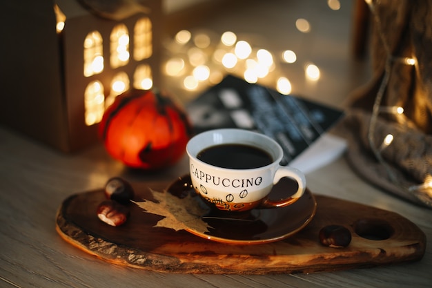 Herbststillleben mit einer Tasse Cappuccino vor dem Hintergrund von Girlandenlichtern