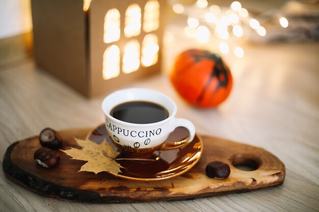 Herbststillleben mit einer Tasse Kaffeekürbis und Blättern auf einem gemütlichen Hintergrund