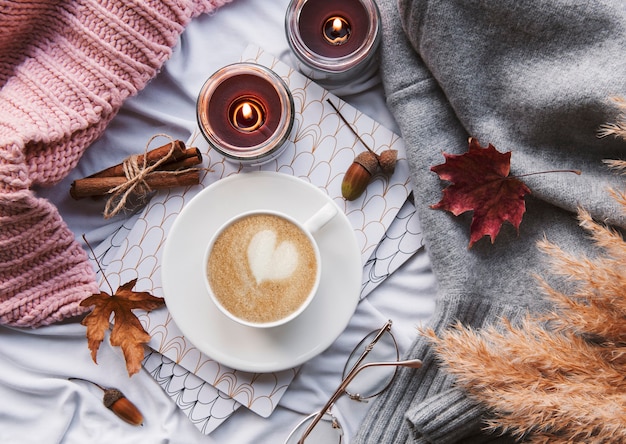 Herbststillleben mit Kürbissen, Kaffee und brennenden Kerzen. Gemütliche Herbstkomposition