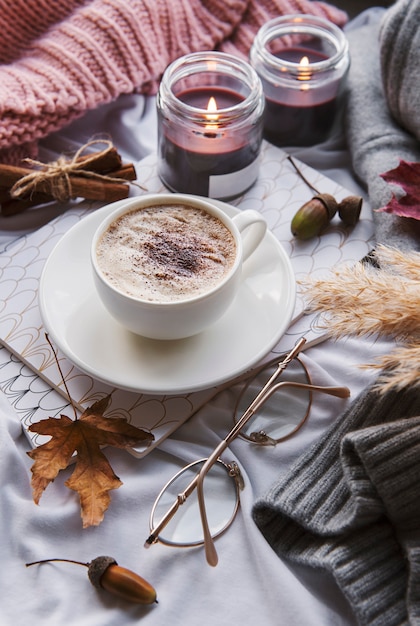 Herbststillleben mit Kürbissen, Kaffee und brennenden Kerzen. Gemütliche Herbstkomposition