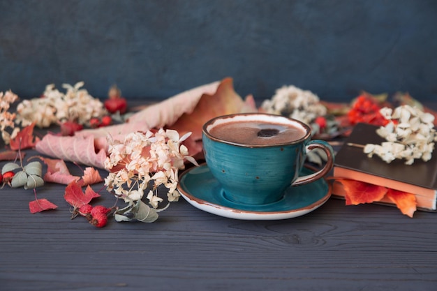 Herbststimmung eine Tasse Kaffee zwischen Herbstlaub auf einem dunklen Holztisch Textur von Blättern und Beeren