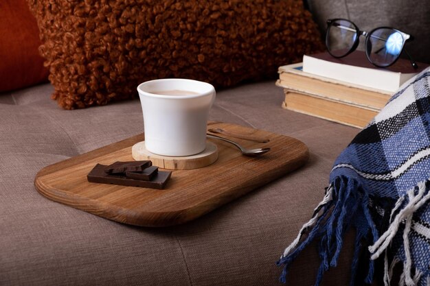 Herbststimmung Hintergrund mit Tasse Kakao Plaid und Bücher auf dem Sofa Heißgetränk im Herbst Konzept