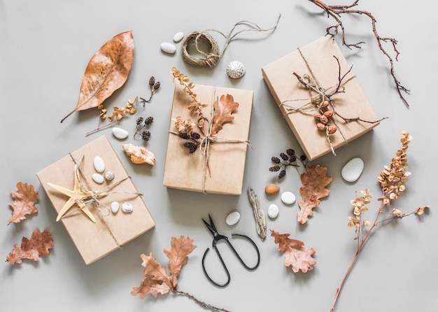 Herbststimmung kreativer Hintergrund Hausgemachte Dekorationsgeschenkboxen mit natürlichen Materialien auf hellem Hintergrund, Draufsicht