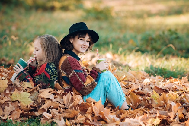 Herbststimmung Paar träumende Mädchen, die eine Tasse heißen Tee oder Saft halten Fröhliche lächelnde Frau mit Schwester