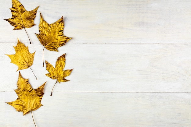 Herbststrauß aus goldbemalten Ahornblättern auf Holz