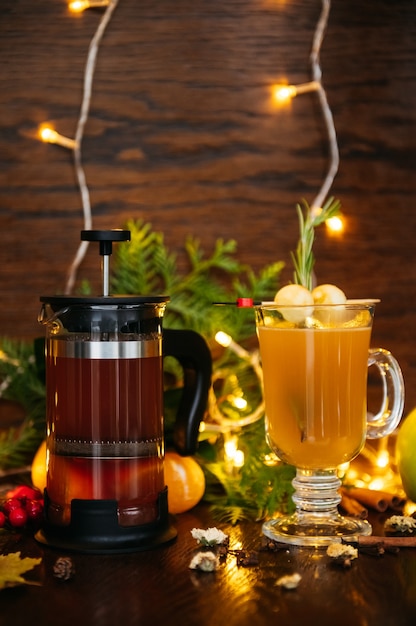 Herbsttee in der französischen Presse und Zitrus-Tee im transparenten Becher mit Apfel, Feijoa und Litschi auf dem Tisch im Restaurant