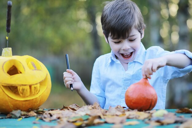 Herbsttraditionen und Vorbereitungen für den Feiertag Halloween. Ein Haus in der Natur, eine Lampe aus Kürbissen schneidet am Tisch aus.