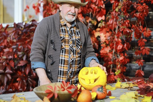 Herbsttraditionen und Vorbereitungen für den Feiertag Halloween. Ein Haus in der Natur, eine Lampe aus Kürbissen schneidet am Tisch aus.