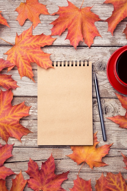 Herbstzusammensetzung mit Arbeitsplatz mit leerem Notizbuch, Bleistift, roter Tasse Kaffee