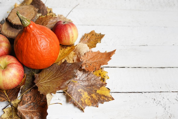 Herbstzusammensetzung mit Kopienraum auf weißem Holz, Kürbis, Äpfeln und Blättern