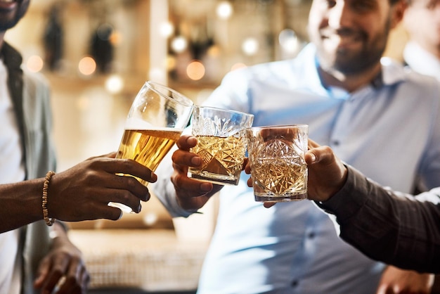 Heres to a great night Schnappschuss einer Gruppe fröhlicher junger Freunde, die nachts in einer Bar einen feierlichen Toast mit ihren Getränken anstoßen