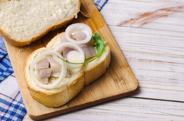 Hering mit weißer Zwiebel auf einem Stück Brot.