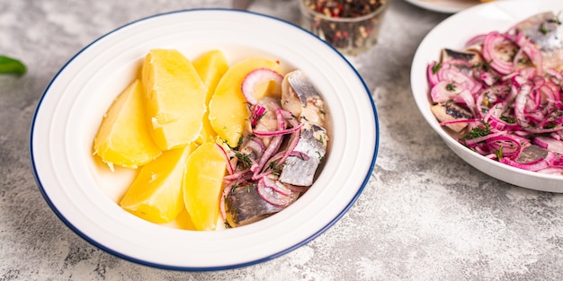 Hering und Kartoffeln zweiter Gang marinierter Fisch Zwiebel frisch verzehrfertig Snack auf dem Tisch