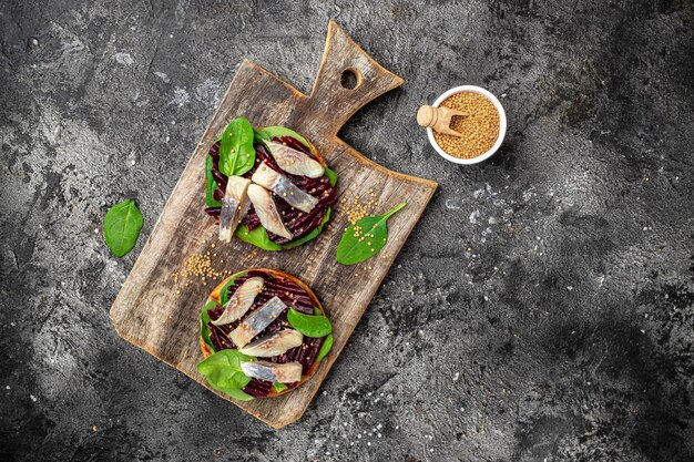 Heringsfilet-Sandwich mit Scheiben von eingelegtem Atlantischen Heringsfilet-Rote-Bete-Salat grüner Spinatzwiebel skandinavische Küche Banner Menü Rezept Ort für Text Draufsicht