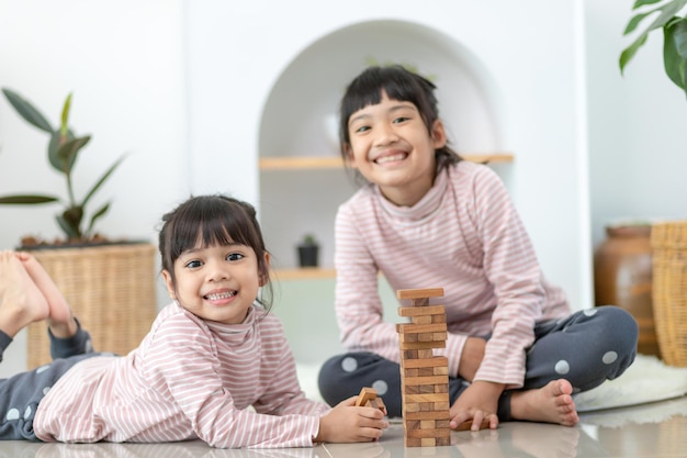 Hermana asiática jugando pilas de madera en casa