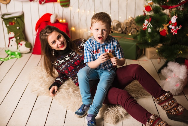 Hermana y hermano pequeño delante del árbol de navidad