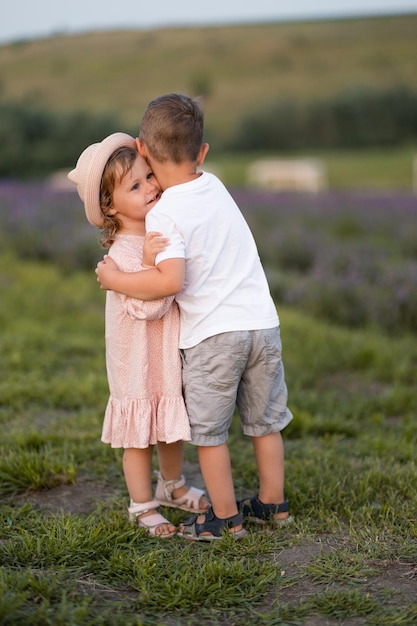 La hermana y el hermano pequeños caminan en un campo de lavanda Los niños lindos caminan y se abrazan en la naturaleza