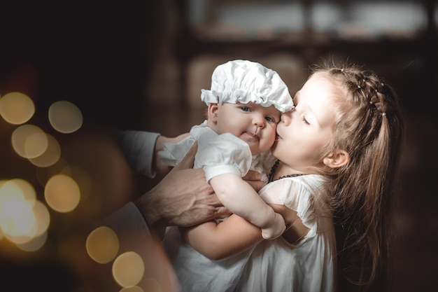 La hermana mayor besa a un bebé con traje bautismal en un templo o iglesia que vino a adorar en una iglesia ortodoxa o bautizar a un bebé