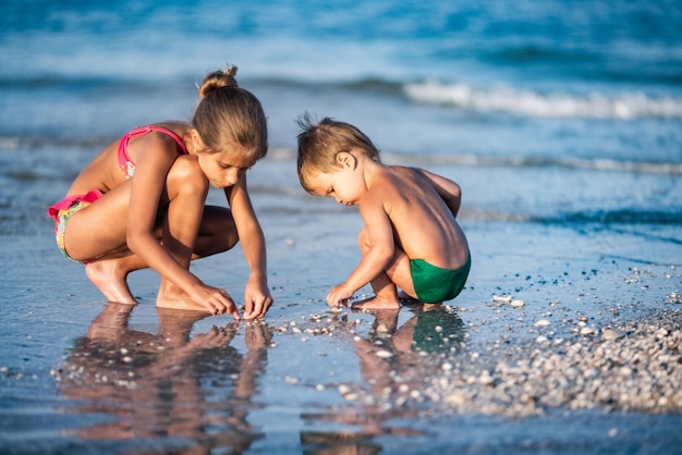 Hermana mayor jugando con su hermano menor encallado cerca de la costa en vacaciones de verano