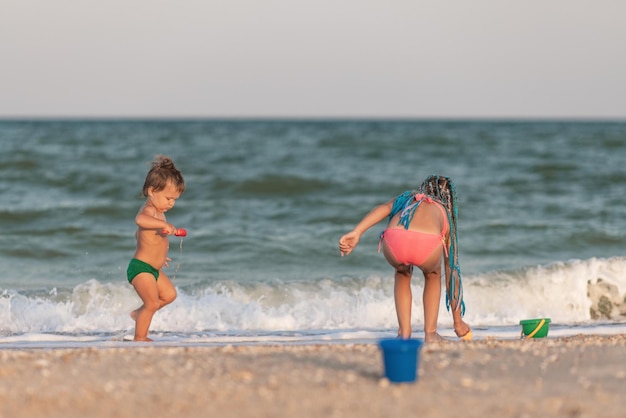 Hermana mayor jugando con su hermano menor encallado cerca de la costa en vacaciones de verano
