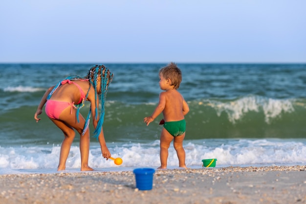 Hermana mayor jugando con su hermano menor encallado cerca de la costa en vacaciones de verano