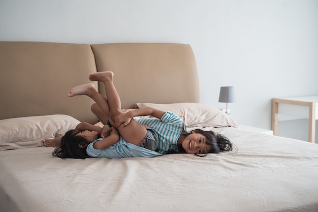 Foto hermana niño divirtiéndose saltando en la cama