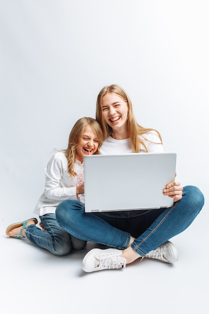 Una hermana o una joven madre con su hija mirando una película en mi computadora portátil, divirtiéndose, riéndose