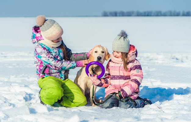 Hermanas abrazando perro en día de invierno