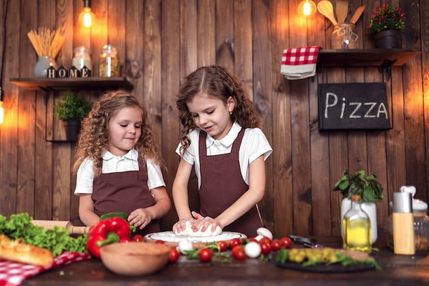 Hermanas alegres cocinando pizza juntos