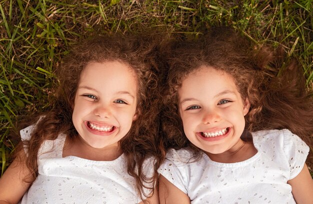 Foto hermanas alegres tiradas en la hierba