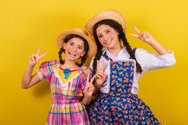 Hermanas y amigas vestidas con ropa típica de la Festa Junina Haciendo el signo de la paz y el amor con los dedos