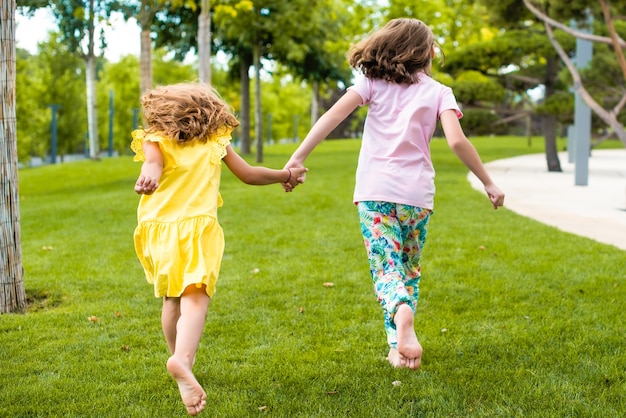 Las hermanas caminan descalzas en la hierba en el parque