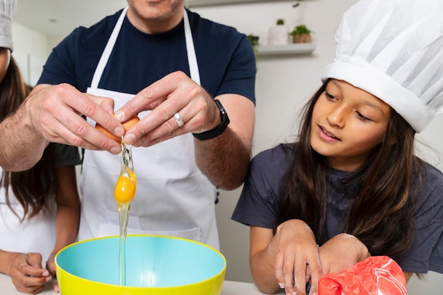 Hermanas cocinando en la cocina con su padre.