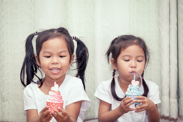 Hermanas se divierten soplando cupcake de cumpleaños juntos, tono de color Vintage