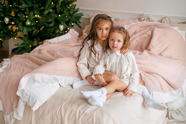 Las hermanas están sentadas en la cama en camisón después de Navidad