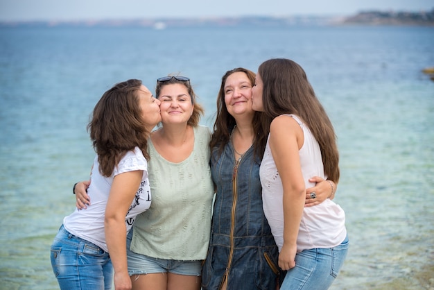 Foto hermanas de la familia feliz de pie sobre un pontón de madera frente al mar en verano.