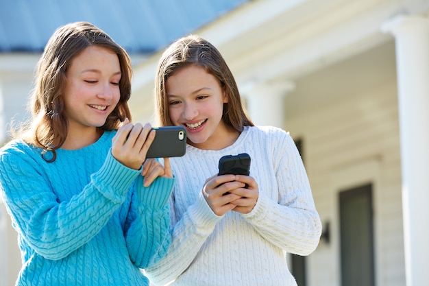 Hermanas gemelas divirtiéndose con tecnología smartphone.