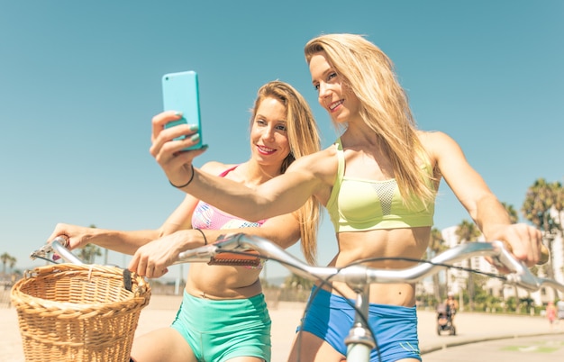 Hermanas gemelas tomando selfie en Los Ángeles en la pasarela de la playa