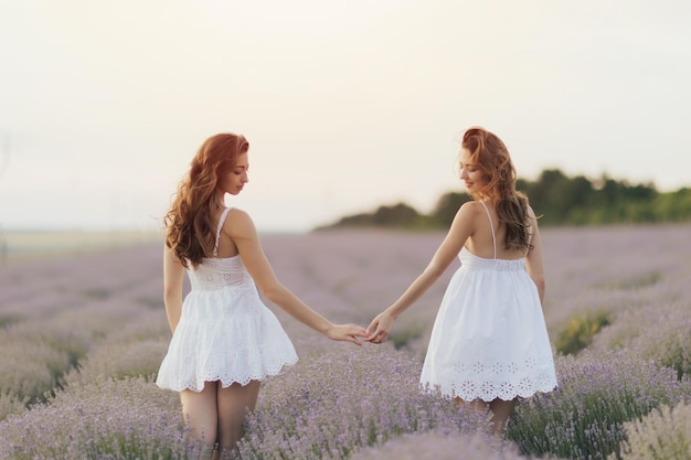 Hermanas jóvenes caminando por el campo de lavanda en Provenza