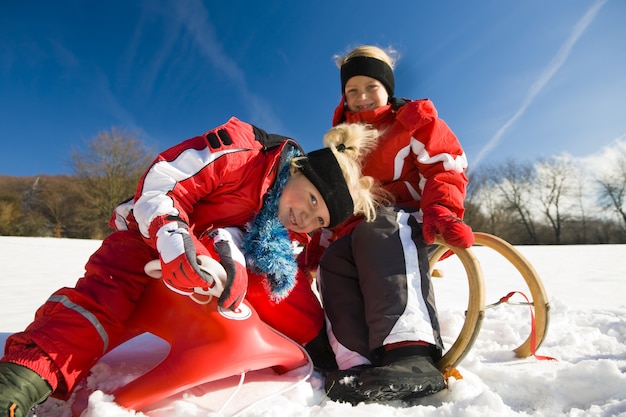 Hermanas en la nieve en trineo