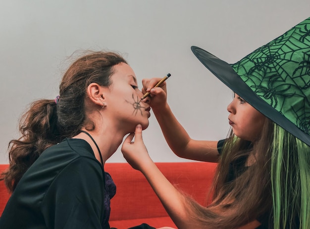 Las hermanas de las niñas caucásicas hacen maquillaje de halloween