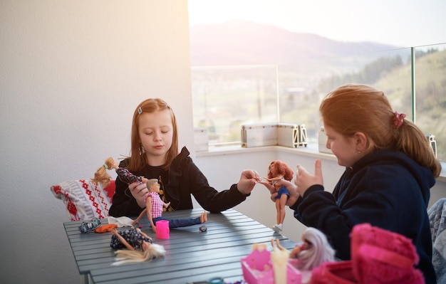 hermanas o amigas niñas jugando con muñecas en el balcón