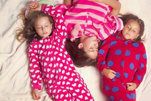 Foto hermanas o amigas en pijama duermen en la cama