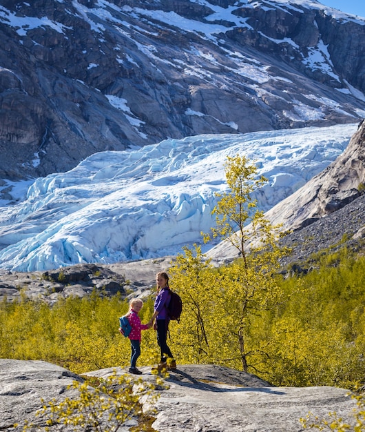 Hermanas de senderismo en las montañas y el glaciar Nigardsbreen al fondo